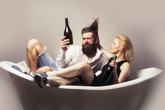 young couple in bath with wine bottles