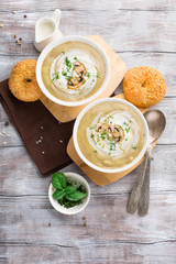 Mushroom cream soup with fried mushrooms and fresh herbs on rustic white wooden table, top view