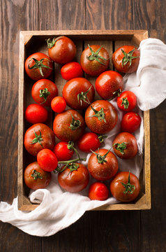Several different fresh organic tomatoes on old rustic background, top view