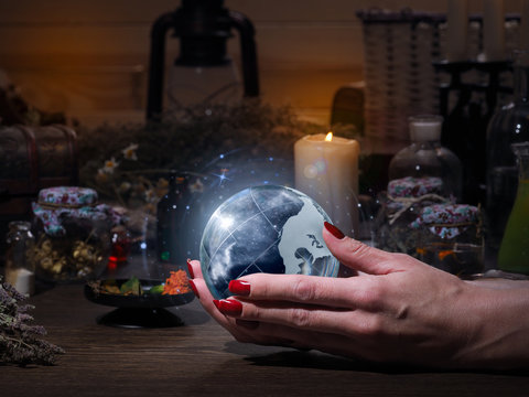 Women's hands holding the magic sphere with the stars. The blue glow. Flasks, retort for alchemy. Concept - the world of astrology, stars, prediction, occult, spirituality, spiritualism