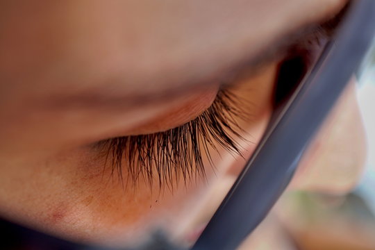 Macro Detail Of A Closed Woman Eye With Extremely Long Black Natural Eyelashes And Dark Brown Eyebrows Behind The Thick Sunglasses 