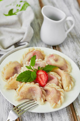 Homemade dumplings with strawberries and sour cream. Top view