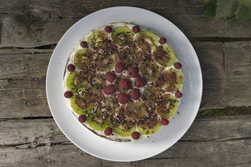 Homemade chocolate cake with raspberries and kiwi on the wooden