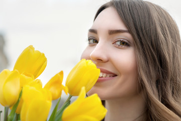 Young woman is yellow tulips flowers in the city.