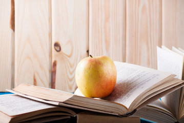 Stack of books and apple on a blue wooden shelf