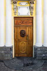 Frontal view of a old red wooden door with yellow house