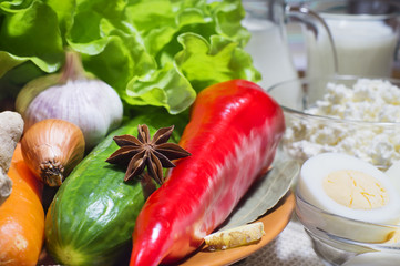 Mix of various organic ripe vegetables, cottage cheese, milk and eggs, close-up. Star anise, peppers, carrots, cucumber, lettuce, onion, garlic, oil and spices. Still life of healthy food.