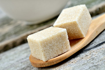 Beige sugar cubes in a wooden spoon