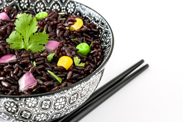 Black rice and vegetables in a bowl isolated on white background

