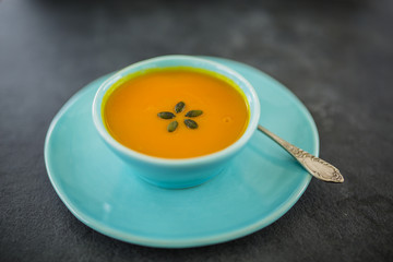 Tasty pumpkin soup in bowl on stone background.
