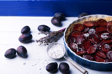Homemade pie with plums and sieve on the table