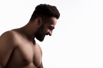Obraz premium Profile of naked handsome man happy smiling isolated on white background. Bearded man looking down in studio.