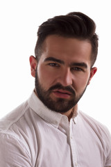 Obraz premium Closeup portrait of handsome hipster man looking at camera in studio. Serious young man in white shirt posing isolated on white background.