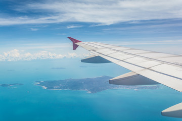 Wing of a plane from window view with Koh Samui in background in Surat Thani, Thailand.