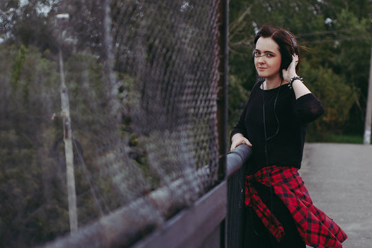 grunge woman listening to music on the bridge
