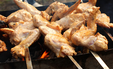 Skewers of chicken wings roasting on the grill