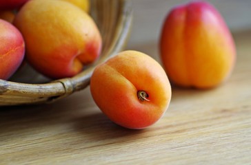 Fresh apricots fruit in wooden basket on a rustic wooden background.