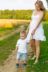 Fototapeta premium Pregnant mom with a boy resting in a meadow.