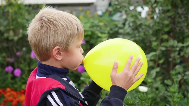 child in the garden inflate a yellow balloon