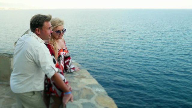 Happy romantic married couple cuddling in love - caucasian man and cute woman lady tourists vacationers near sea
