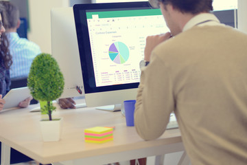 Rear View Of A Businessman Analyzing Graph On Computer