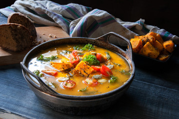 Pumpkin soup with tomatoes and herbs in a rustic style. 