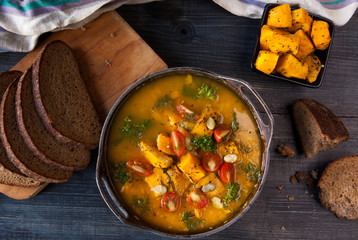 Pumpkin soup with tomatoes and herbs in a rustic style. 