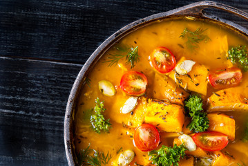Pumpkin soup with tomatoes and herbs in a rustic style. 