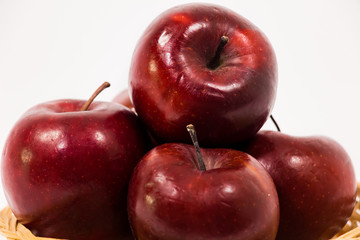 Close up of ripe red apples in wicker basket isolated on white background