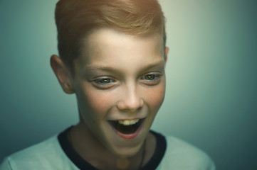 Surprised blond happy teenage boy with stylish haircut and bright eyes, studio portrait.