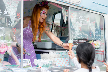 Lady with red hair wearing spotted apron serving ice cream