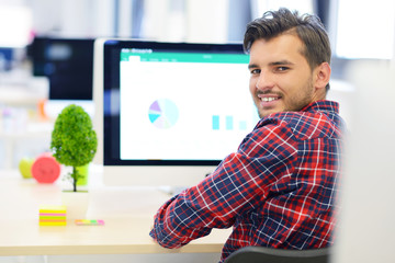 Rear View Of A Businessman in startup office Analyzing Graph On Computer
