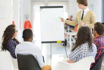 Obraz premium business, education and office concept - serious business team with flip board in office discussing something