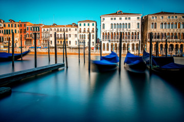 Venice cityscape view on Grand canal with colorful buildings and boats at the sunrise. Long exposure image technic with motion blurred boats and glossy water - obrazy, fototapety, plakaty