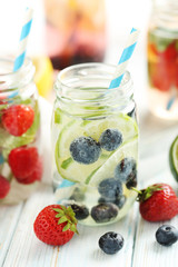 Detox water in bottles with berries on wooden table