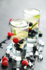 Detox water in glasses with berries on wooden table
