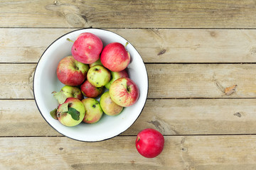 ripe red apples in bowl on wooden background