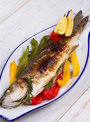 Whole grilled seabuss fish with colorful peppers, lemon and rosemary