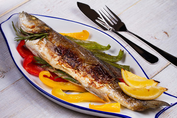 Whole grilled seabuss fish with colorful peppers, lemon and rosemary