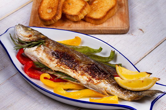 Whole grilled seabuss fish with colorful peppers, lemon and rosemary
