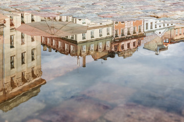 Baltic city Riga in Latvia reflecting in water puddle.