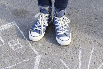 Feet girl in sneakers cost about drawing a chalk on the pavement