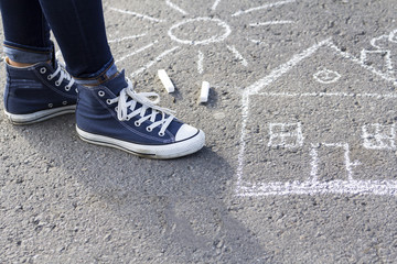 About drawing with chalk on the pavement feet in fashionable sneakers