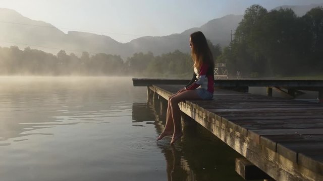 Pensive woman on pier of mountain lake