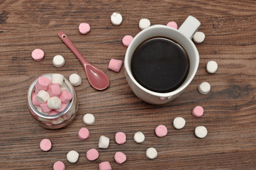 A mug and a jar filled with small marshmallows and a little pink