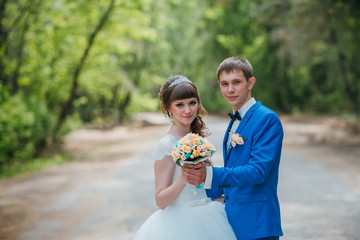 young bride and groom kissing on the background of the forest the road