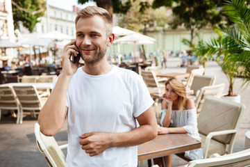 Man speaking on phone while his girlfriend being bored.