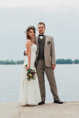 young groom and bride standing hugging on the background of the river