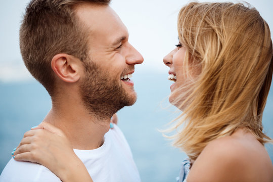 Young beautiful couple smiling, rejoicing, sea background.