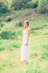 Fototapeta na wymiar bride stands on a background of grass and mountains